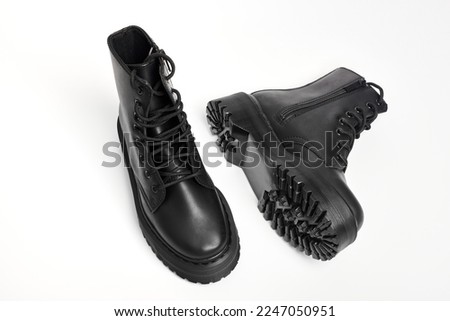 Black women combat boots on high heel platform with lug soles lying on isolated white background. Military stylish high heel platform combat boots for woman legs, new footwear trends Royalty-Free Stock Photo #2247050951