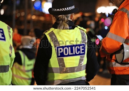 Police officer in hi-visibility jacket policing crowd control at an outside UK event Royalty-Free Stock Photo #2247052541