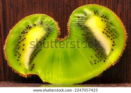 Double kiwi fruit (kiwi butterfly) cut in half on brown wood background