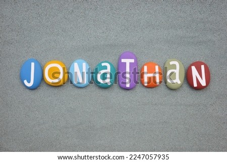 Jonathan, male given name composed with multi colored stone letters over green sand