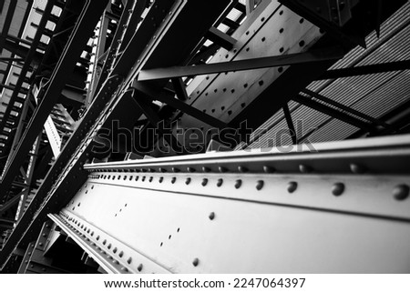 Steel beams with rivets and screws forming the compilicated construction of the historic “Müngstener Brücke“ railway bridge in Solingen Germany from 1897. Frog perspective in black and white. Royalty-Free Stock Photo #2247064397