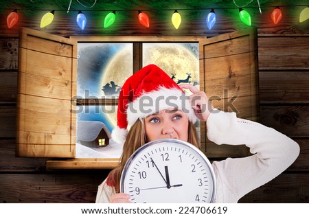 Festive blonde showing a clock against santa delivery presents to village