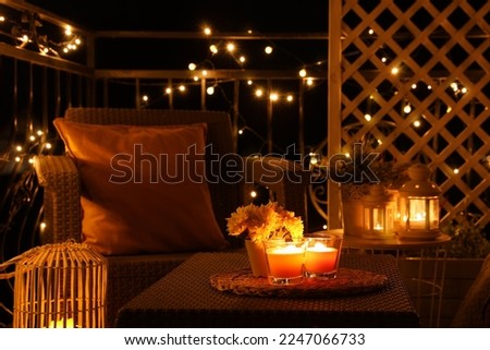 Beautiful view of garden furniture with pillow and burning candles at balcony Royalty-Free Stock Photo #2247066733