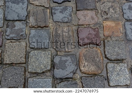 Granite dirty paving stones in the city. Road from paving stones for background and texture. The old road of granite paving stones.