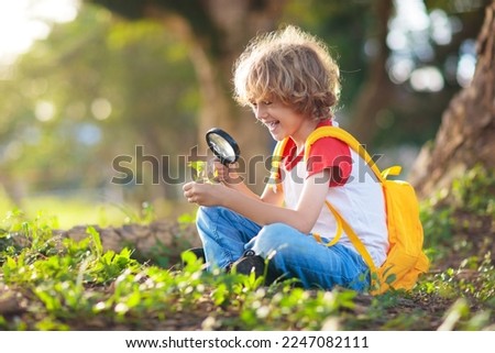 Kids explore nature. Children hike in sunny summer park. Scout club and science outdoor class. Boy and girl watch plants through magnifying glass. Kid exploring environment. Young explorer adventure. Royalty-Free Stock Photo #2247082111