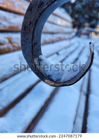 Close up of rusty metal chain on the bench. Winter card with outgoing perspective on wooden bench on the city park. Winter street.