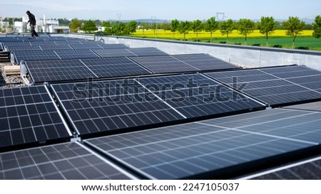 Male team engineers installing stand-alone solar photovoltaic panel system. Electricians mounting blue solar module on roof of company roof. Alternative energy concept Royalty-Free Stock Photo #2247105037