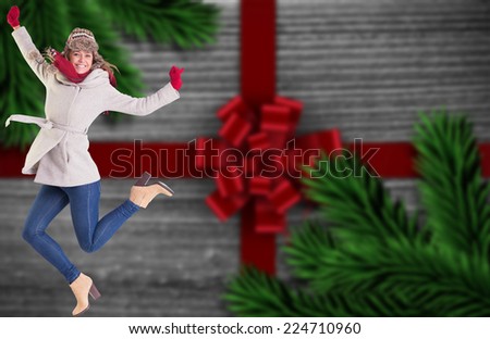 Happy blonde in winter clothes posing against festive bow over wood