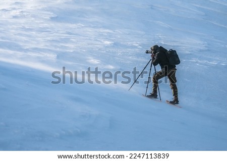 A photographer working in winter conditions using tripod 