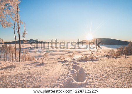 Footprints of the first climber to reach the summit during sunrise in Beskydy mountains, Czech republic. Breathtaking winter scenery with a view of passing clouds and sun. Hiking lifestyle. Royalty-Free Stock Photo #2247122229