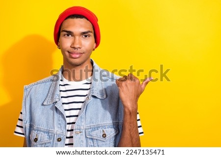 Photo of attractive young man wear trendy outfit arm direct empty space presenting announcement offer isolated on yellow color background