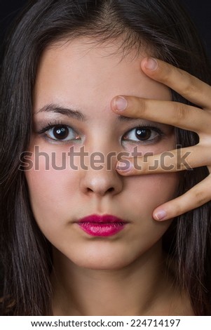 beautiful young asian girl with her fingers on her face
