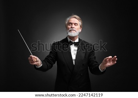 Professional conductor with baton on black background Royalty-Free Stock Photo #2247142119