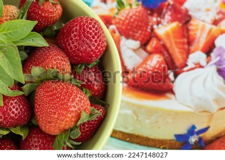 Fresh strawberries in bowl against the background of picture with strawberry cheesecake recipe.