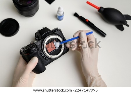 Hands hold a professional sensor cleaning swab and clean the matrix from dust and dirt.Cleaning and maintenance of the mirrorless camera sensor. Care concept for professional photography equipment.  Royalty-Free Stock Photo #2247149995