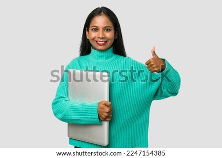 Young indian woman holding a laptop isolated on white background