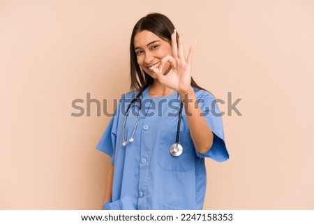 Young nurse colombian woman isolated cheerful and confident showing ok gesture.