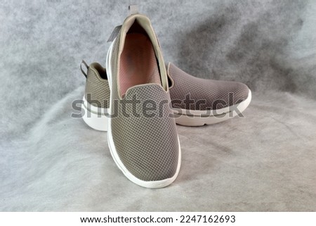 The picture shows women's shoes, gray slip-ons, on a white background, top view.