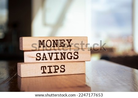 Wooden blocks form the words 'Money savings tips' on blur background. Business concept.