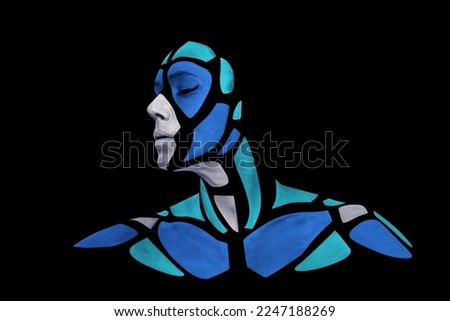 Portrait of a human with creative art makeup posing in the studio. Shape of silver gray and colored blue polygons on beautiful face, neck and shoulders. Parts of face isolated on black background. Royalty-Free Stock Photo #2247188269