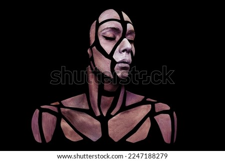 Portrait of a human with creative art makeup posing in the studio. Shape of polygons on beautiful face, neck and shoulders. Parts of face isolated on black background.