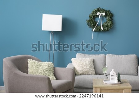 Interior of living room with Christmas wreath, sofa and armchair