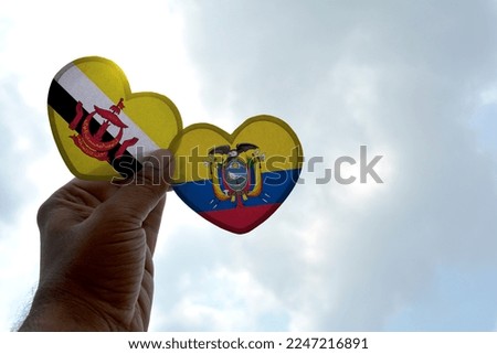 Hand holds a heart Shape Brunei and Ecuador flag, love between two countries