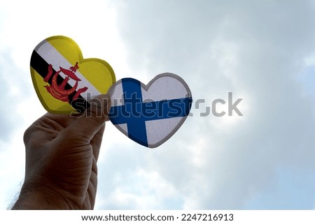 Hand holds a heart Shape Brunei and Finland flag, love between two countries
