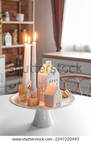 Stand with candle holders and Christmas balls on dining table in kitchen