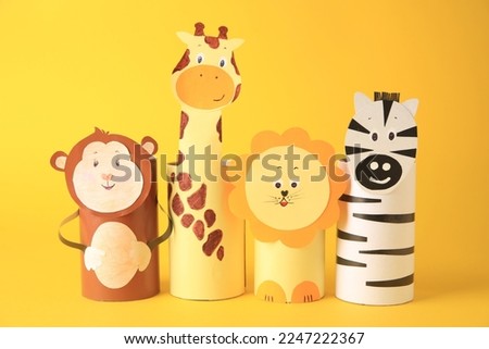 Toy monkey, giraffe, lion and zebra made from toilet paper hubs on yellow background. Children's handmade ideas