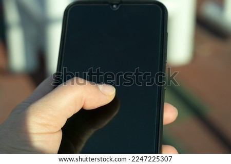 Woman hand holding her smartphone outside.