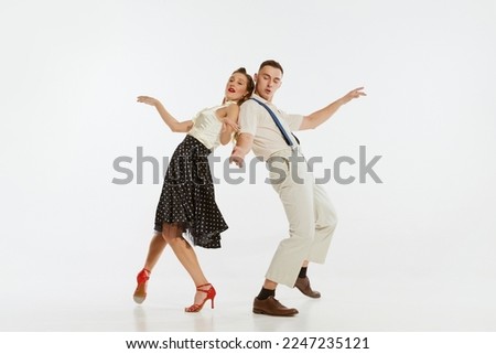 Love in motion. Young excited man and woman wearing 60s american fashion style clothes dancing retro dance isolated on white background. Music, energy, happiness, mood, action Royalty-Free Stock Photo #2247235121