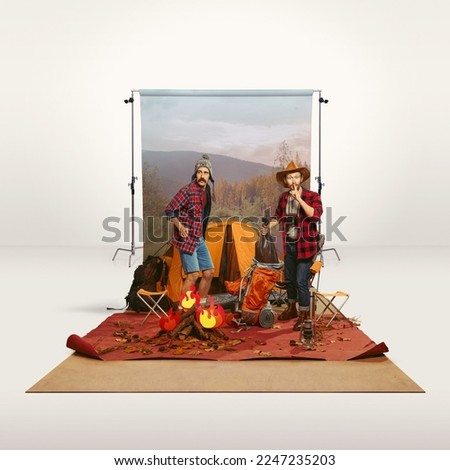 Two mates, men recreating camping activity on grey background with nature wallpaper. Imagination, inspiration, dreams. Concept of travelling, active lifestyle, friendship, leisure activity, relaxation