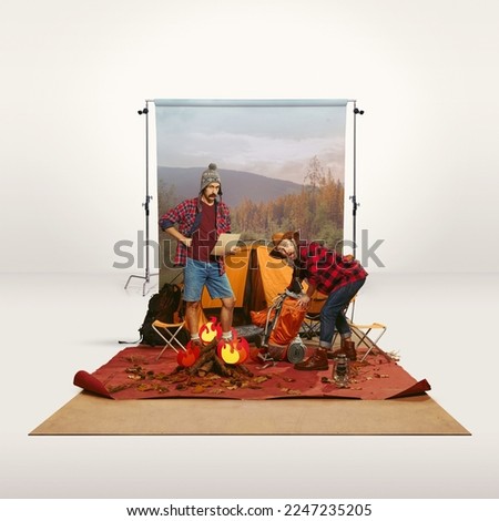 Two mates, men recreating camping activity over grey background with nature wallpaper. Setting tent. Concept of travelling, active lifestyle, friendship, leisure activity, relaxation