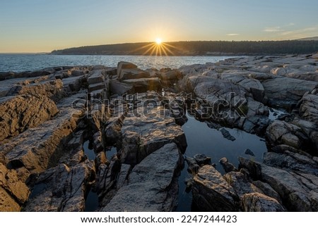 Starburst sunset over a tide pool from Otter Point overlook in Acadia National Park Maine 