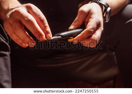 male hands carve wood with a knife