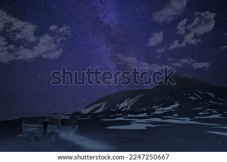 Milky way over the top of a volcano, with tour bus at night.