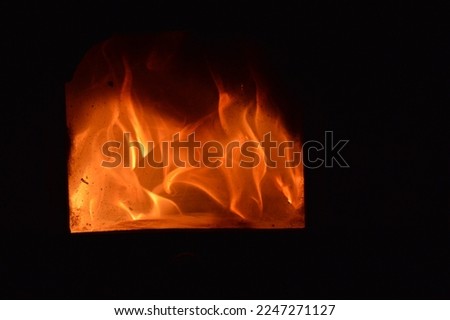 Closeup of the flames of a fireplace behind a dirty glass door, isolated night picture