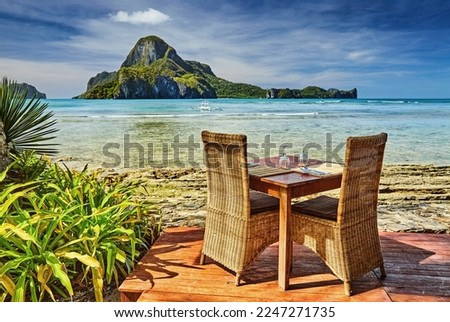 Outdoor terrace of the beach restaurant in front of sea with table and chairs, beautiful view to the Cadlao island, El Nido, Philippines Royalty-Free Stock Photo #2247271735