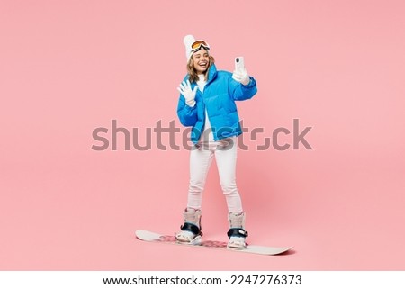 Snowboarder fun woman wear blue suit goggles mask hat ski padded jacket do selfie shot mobile cell phone isolated on plain pastel pink background. Winter extreme sport hobby weekend trip relax concept