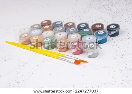 A set of colorful gouache paints, brushes and canvas with numbers is ready for drawing education. Hobby and leisure activity. Background with copy space