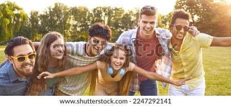 Happy, funny, positive friends hugging, looking at the camera and smiling. Diverse group of cheerful young people enjoying beautiful summer day, spending time outside and having fun together