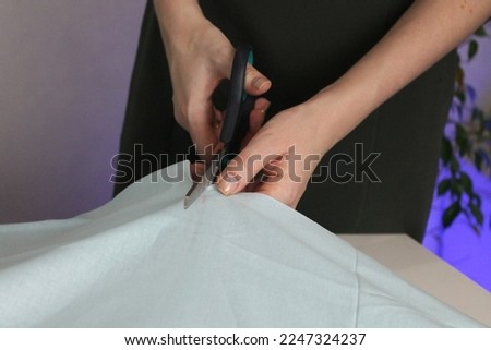 cutting out fabric with ruler, chalk and scissors, cutting fabric, needlework, preparing fabric for sewing, cotton, dressmaker cuts the fabric of a dress on a sketch line, a fashion designer-tailor