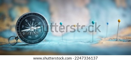 Magnetic old compass and pins on world map. Travel, geography, navigation, tourism and exploration concept wide background. Macro photo. Very shallow focus.