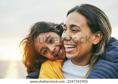 Happy latin mother and daughter having fun during winter time - Focus on mom face