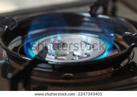 Portable kitchen gas stove with a burning blue flame.