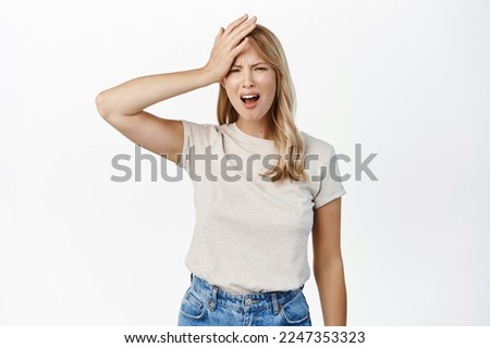Disaster. Troubled blond girl holding hand on head and grimacing, feeling disappointed, upset by smth, standing over white background Royalty-Free Stock Photo #2247353323