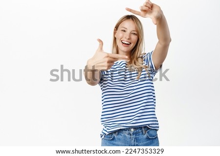 Getting creative. Smiling young woman taking picture, looking through hand frames gesture to measure smth, take shot, photographing, standing over white background