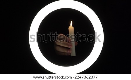 female hands light a candle close-up on a black background. burning fire on a candle stick. The concept of ritual actions.