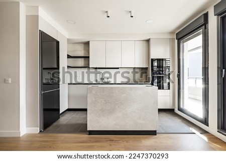 Front view of a modern designer kitchen with smooth handleless cabinets with black edges, black glass appliances, a marble island and marble countertops Royalty-Free Stock Photo #2247370293